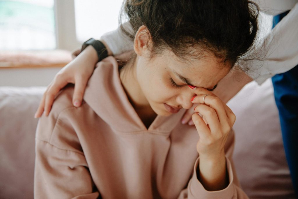Eine junge Frau erfährt emotionale Unterstützung durch eine Freundin in einer tröstenden Umarmung.
